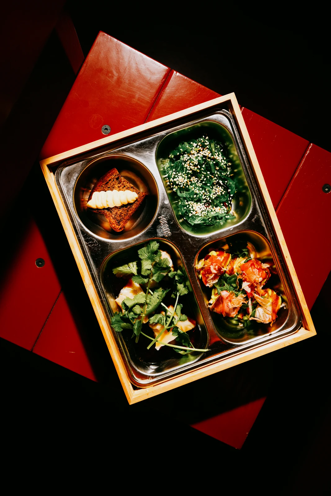 Otwarty bentobox z ryżem, panierowanym mięsem, sałatką i marynowanymi warzywami w przegrodach